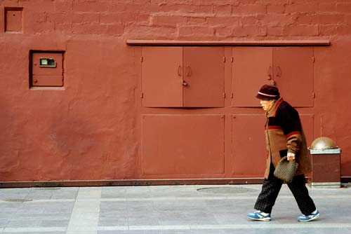 old lady and red wall-AsiaPhotoStock